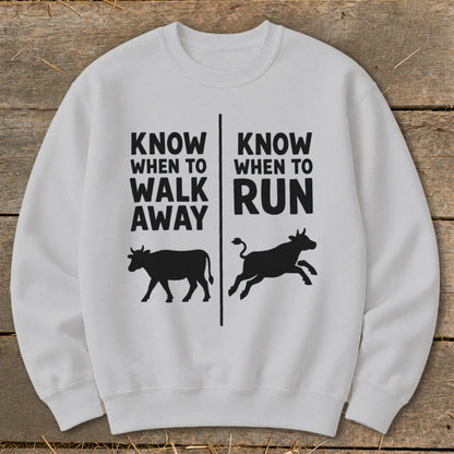 White crewneck sweatshirt with black text and cow silhouettes: "Know When to Walk Away" and "Know When to Run".