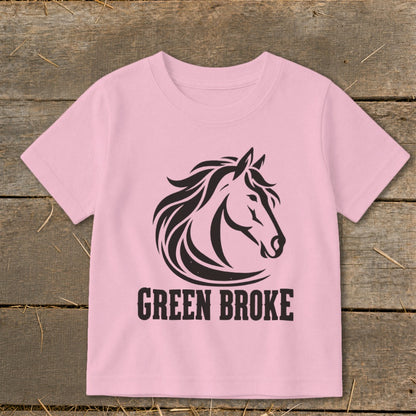 A pink short-sleeved children's t-shirt featuring a black horse head graphic and the text GREEN BROKE.