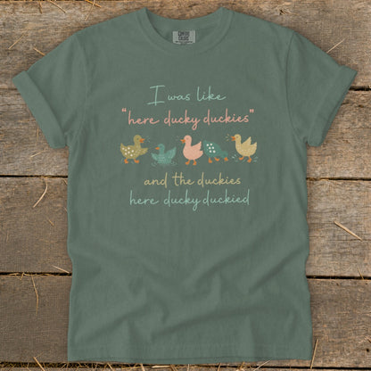 Sage green t-shirt with "I was like 'here ducky duckies' and the duckies here ducky duckied" text and duck illustrations.