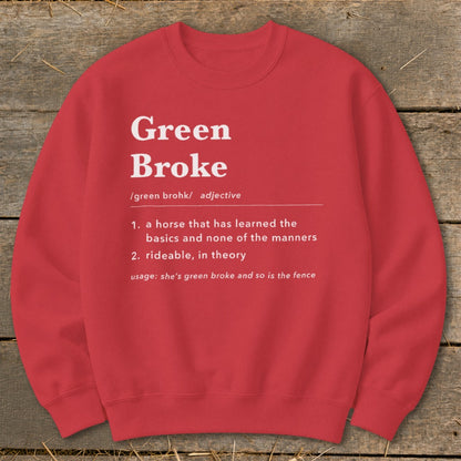 Red crewneck sweatshirt with white text defining "Green Broke" laid on a wooden surface.
