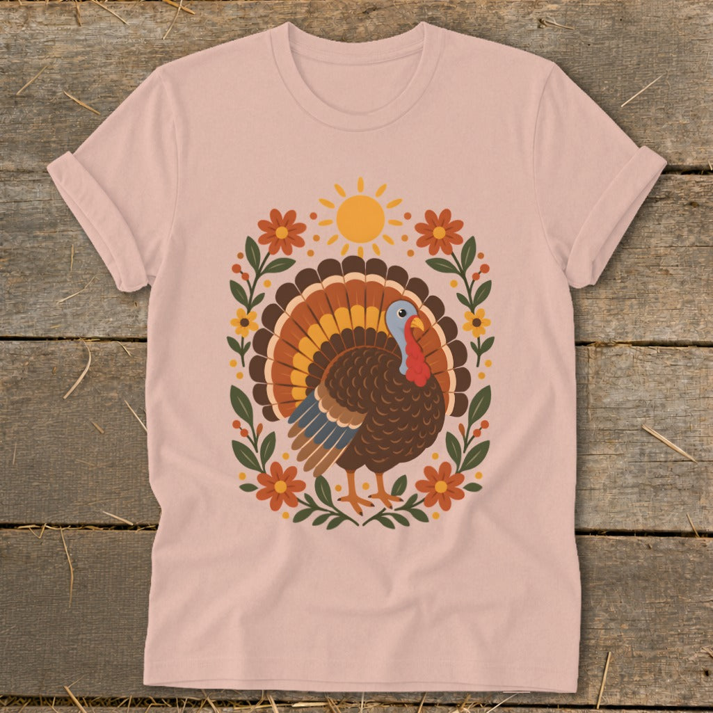 Pink t-shirt with a festive turkey, sun, and floral graphic.