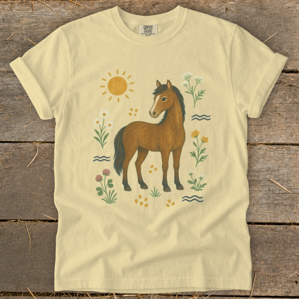 Yellow t-shirt with a brown horse, sun, flowers, and water illustrations.