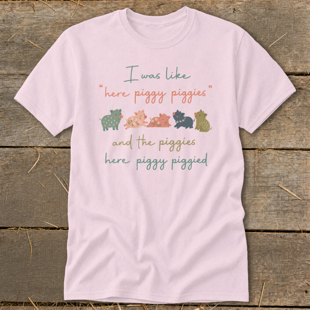 Light pink t-shirt with "I was like, here piggy piggies and the piggies here piggy piggied" text and row of cartoon pigs.