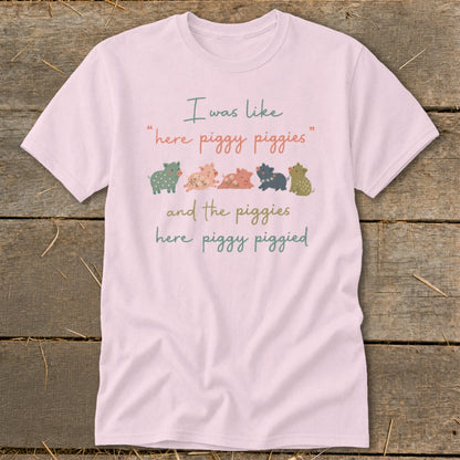 Light pink t-shirt with "I was like, here piggy piggies and the piggies here piggy piggied" text and row of cartoon pigs.