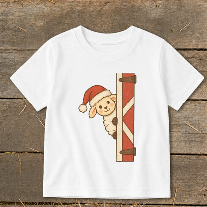 White t-shirt with a cartoon sheep wearing a Santa hat peeking from behind a red wooden door.