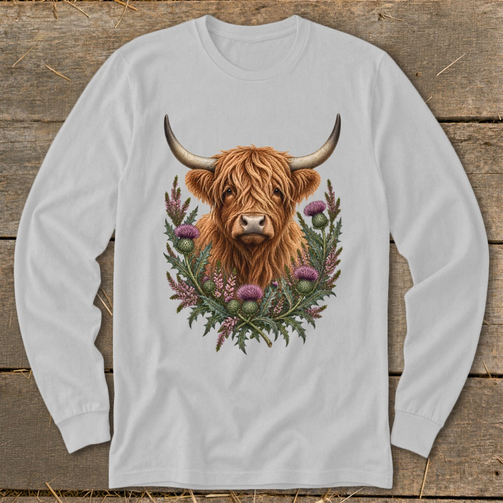 Highland cow portrait surrounded by thistles on a light grey long-sleeve shirt.