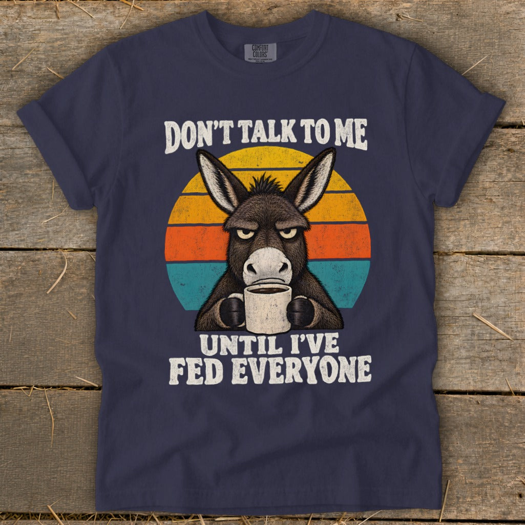 Navy blue t-shirt featuring a grumpy donkey drinking coffee against a retro sunset with white text.