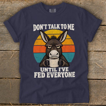 Navy blue t-shirt featuring a grumpy donkey drinking coffee against a retro sunset with white text.