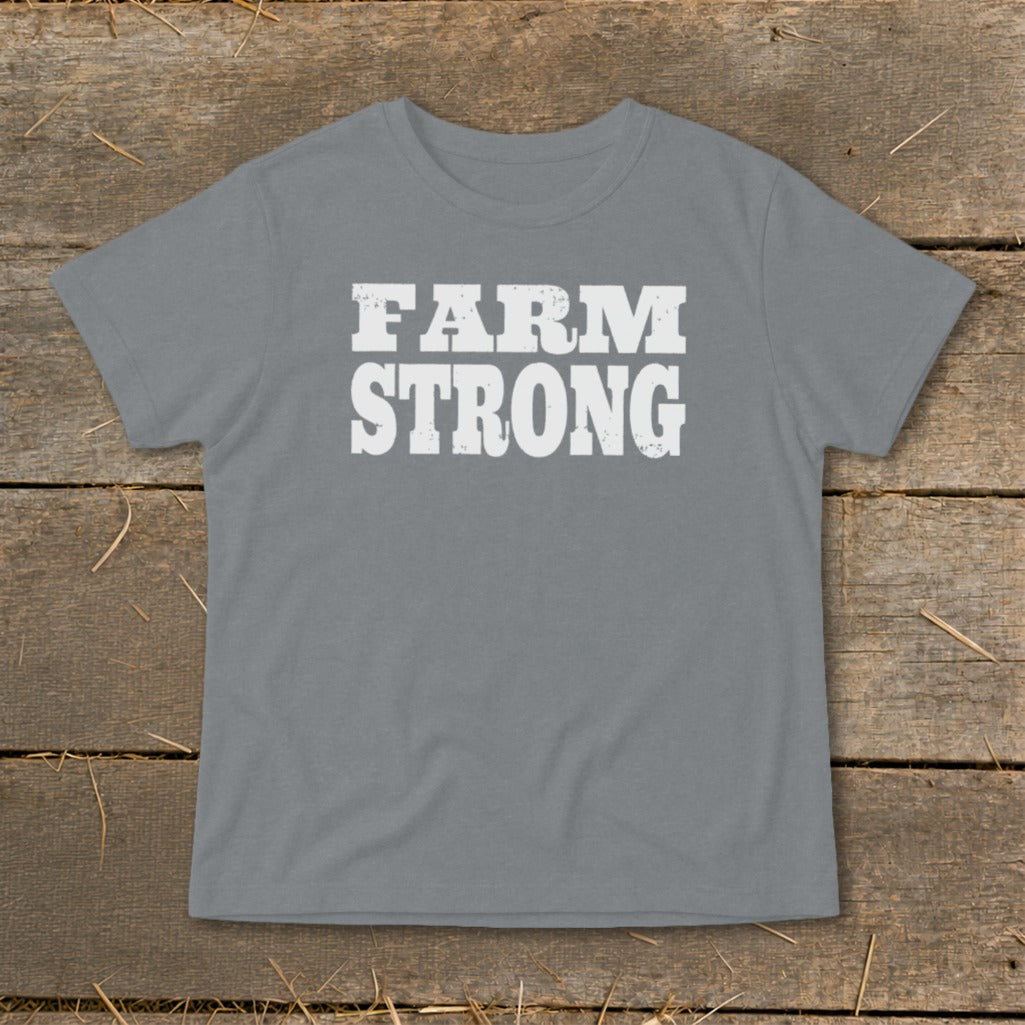 Gray short-sleeved t-shirt with distressed white text reading FARM STRONG, displayed flat on a wooden surface.