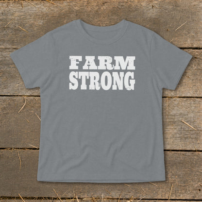 Gray short-sleeved t-shirt with distressed white text reading FARM STRONG, displayed flat on a wooden surface.