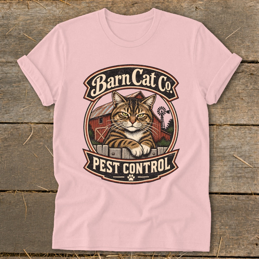 A light pink t-shirt featuring a vintage round graphic of a tabby cat behind a fence with the text Barn Cat Co Pest Control.