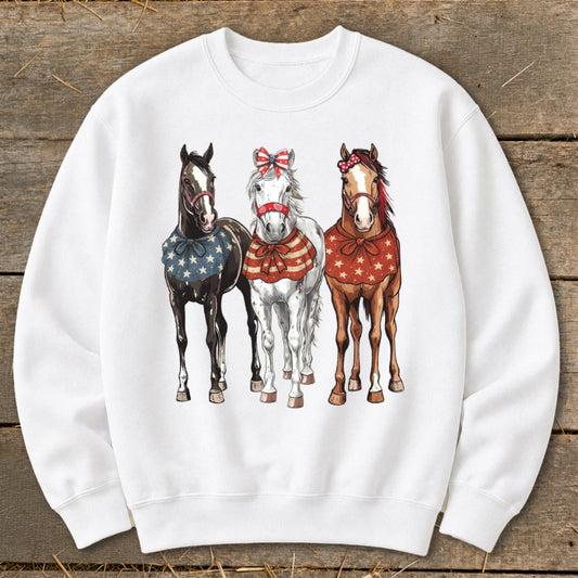 Three horses with patriotic neckerchiefs and bows on a white sweatshirt.
