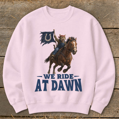 Cat wearing bandana riding horse holding tattered flag with horseshoe, text "WE RIDE AT DAWN".