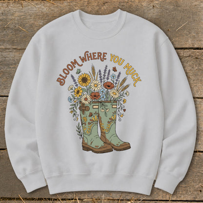 Light grey sweatshirt with "Bloom Where You Muck" text and a floral design.