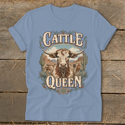 Light blue t-shirt design with "Cattle Queen" text and a longhorn cow in a desert landscape.