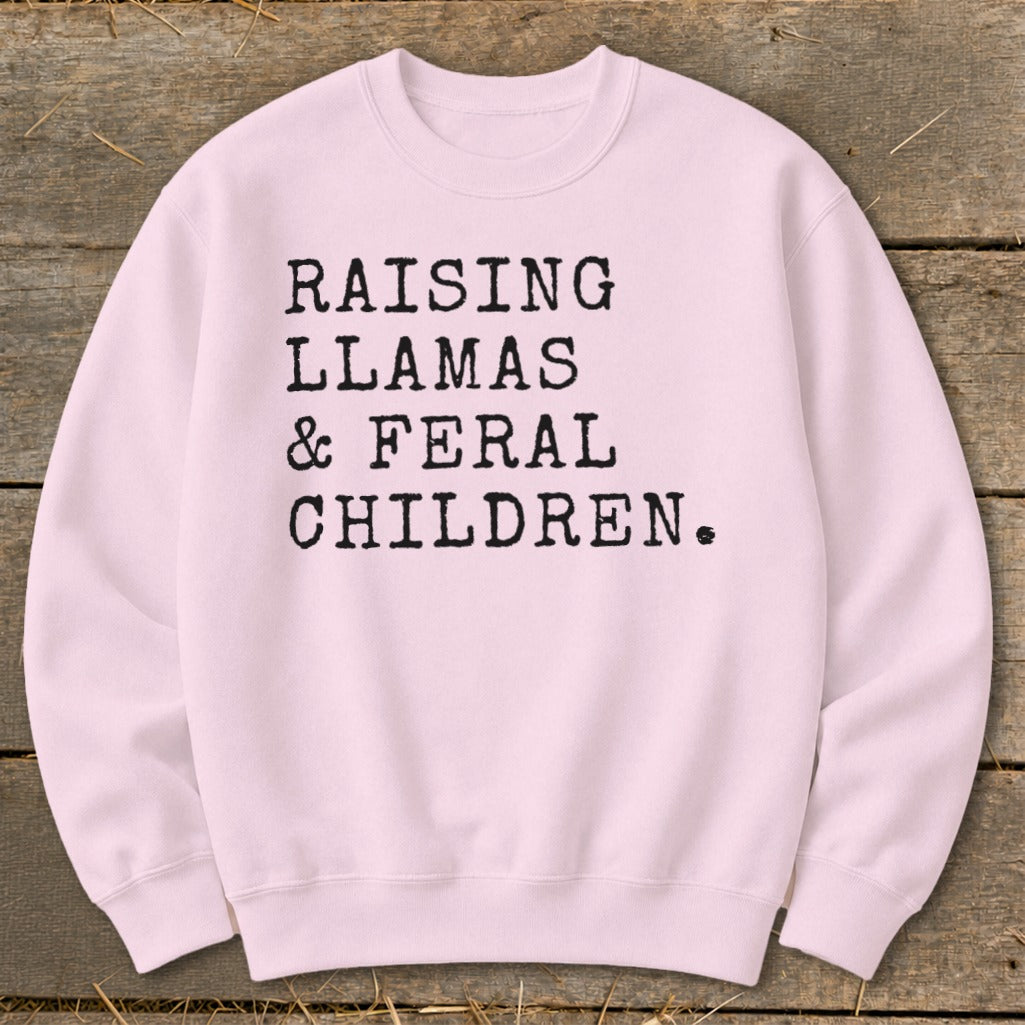 Pink crewneck sweatshirt with black text reading "Raising Llamas & Feral Children."