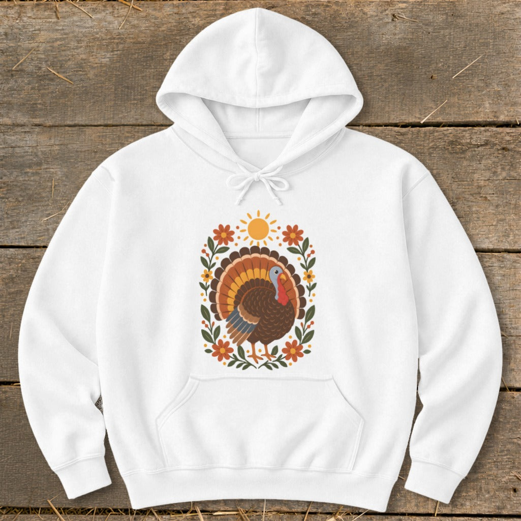White hoodie with a decorative turkey, sun, and floral border graphic.