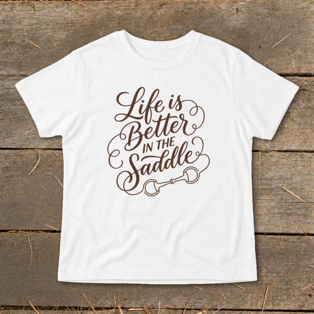 White t-shirt with brown text "Life is Better IN THE Saddle" and horse bit graphic.