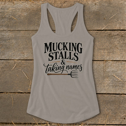 Gray tank top with text "MUCKING STALLS & Taking names" and a pitchfork.