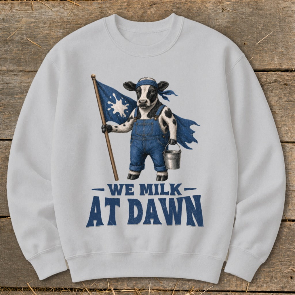 Cow in overalls holding a flag with milk splash, text "We Milk At Dawn".