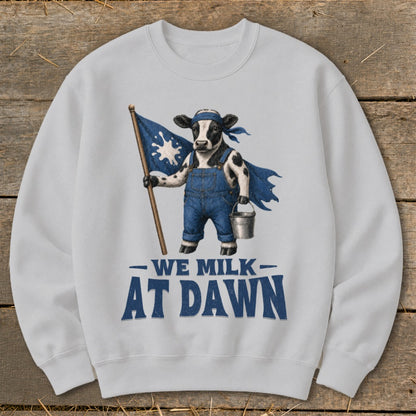 Cow in overalls holding a flag with milk splash, text "We Milk At Dawn".