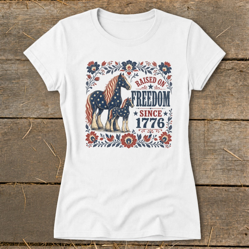White t-shirt with patriotic horses and "Raised on Freedom Since 1776" text.