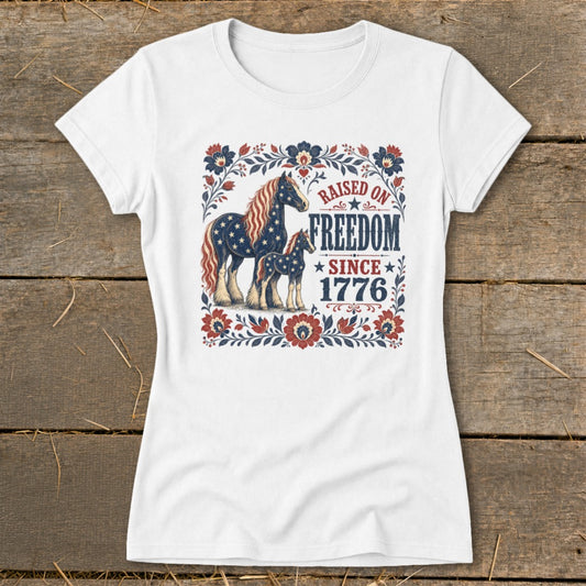 White t-shirt with patriotic horses and "Raised on Freedom Since 1776" text.