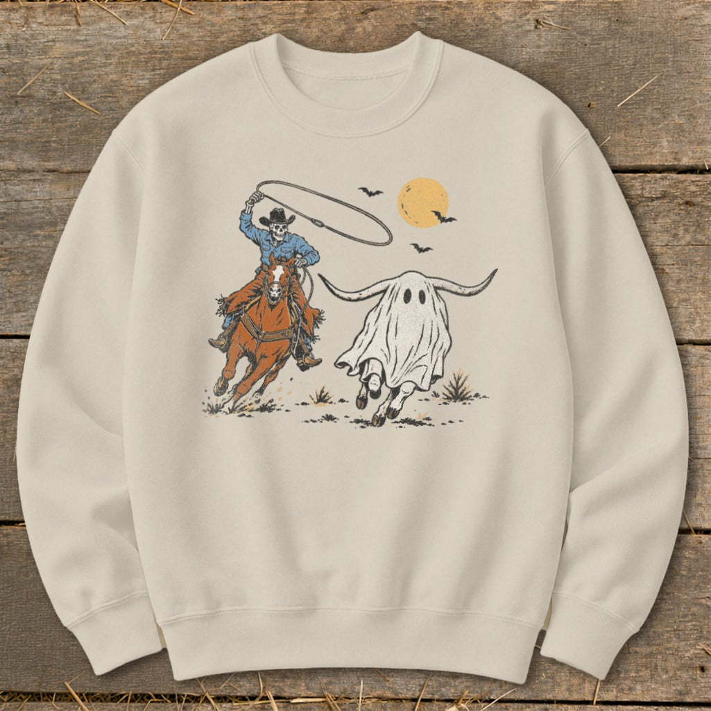 Skeleton cowboy on horseback lassoing a ghost longhorn under a full moon.