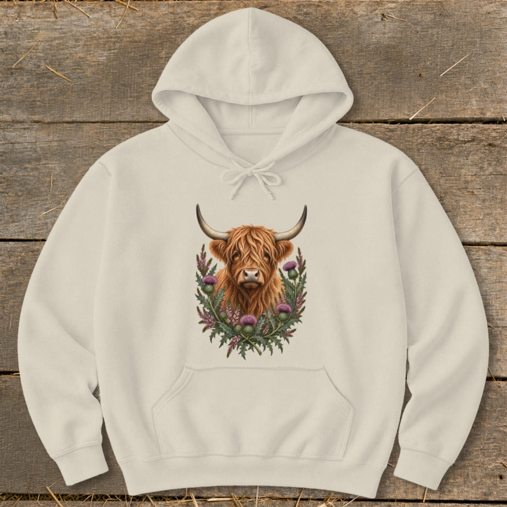 Cream hoodie with a Highland cow illustration surrounded by thistles.