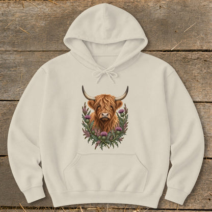 Cream hoodie with a Highland cow illustration surrounded by thistles.