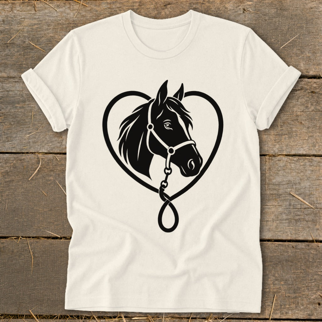 An off-white t-shirt featuring a black graphic of a horse's head framed by a heart-shaped rein on a wooden background.