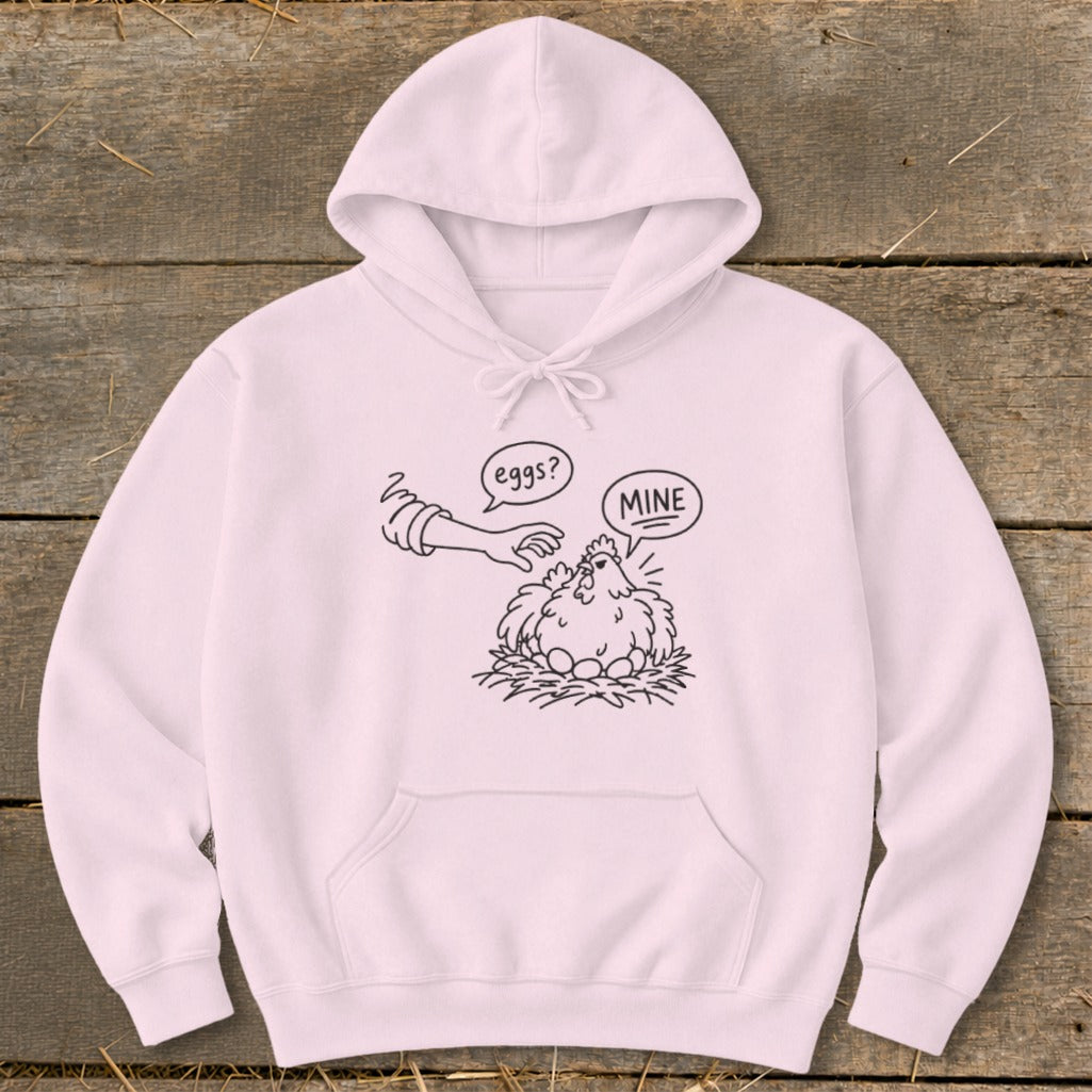 Light pink hoodie with a black line drawing of a hen on eggs saying "MINE" to a hand asking "eggs?".