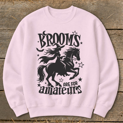 Pink sweatshirt with black Halloween graphic: witch on horse, "BROOM'S ARE FOR AMATEURS".