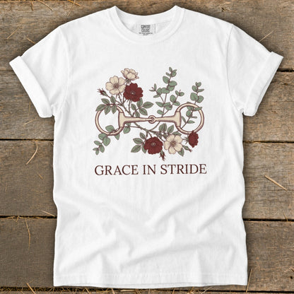 White t-shirt with floral design and horse bit, text "GRACE IN STRIDE".