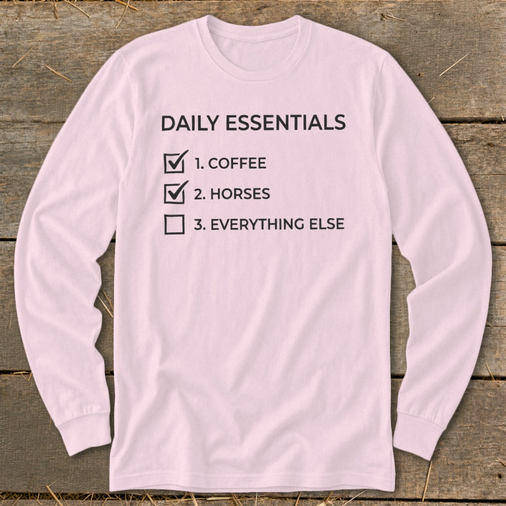 Pink long-sleeve shirt with "Daily Essentials" checklist: 1. Coffee, 2. Horses, 3. Everything Else.