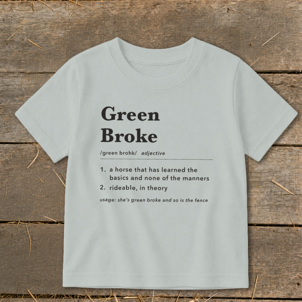Light gray short-sleeve t-shirt with black dictionary definition text reading Green Broke on a rustic wooden background.