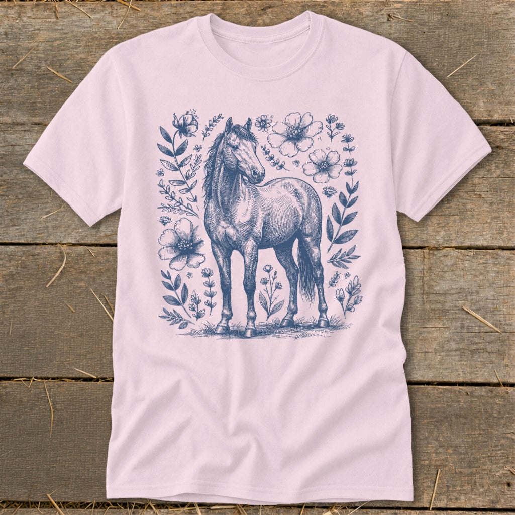 Pink t-shirt with a blue sketched horse surrounded by floral elements.