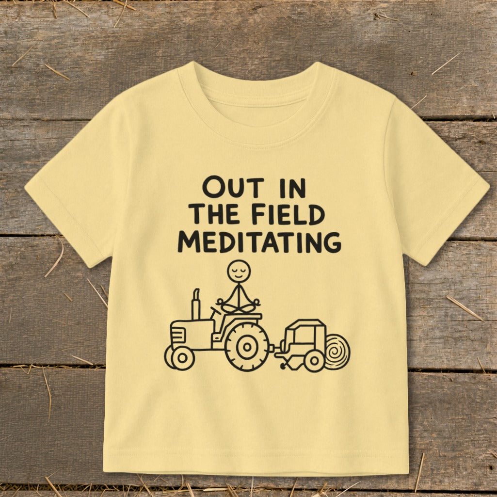 T-shirt with text "OUT IN THE FIELD MEDITATING" and a drawing of a tractor with a figure meditating on it.