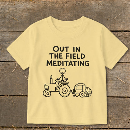 T-shirt with text "OUT IN THE FIELD MEDITATING" and a drawing of a tractor with a figure meditating on it.