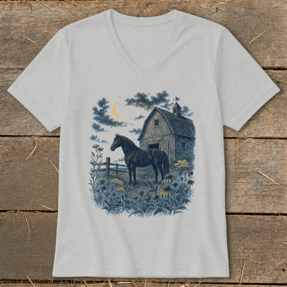 Black horse in field by barn under crescent moon and cloudy sky.