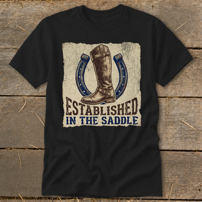 Black t-shirt with a graphic of a riding boot and horseshoes, reading "Established In The Saddle."