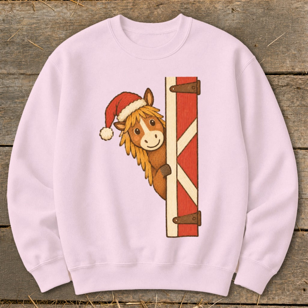 Pink sweatshirt featuring a cartoon horse wearing a Santa hat peeking from behind a barn door.