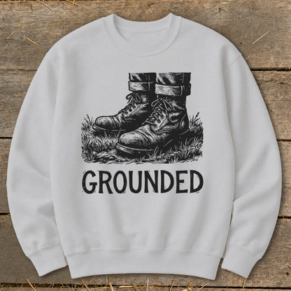 White sweatshirt with black graphic of boots in grass and the word "GROUNDED".