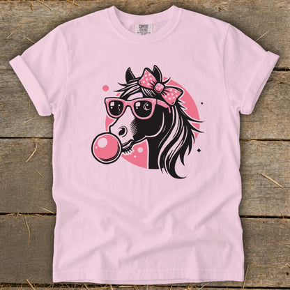 Pink t-shirt with black horse wearing sunglasses and bow blowing bubblegum.