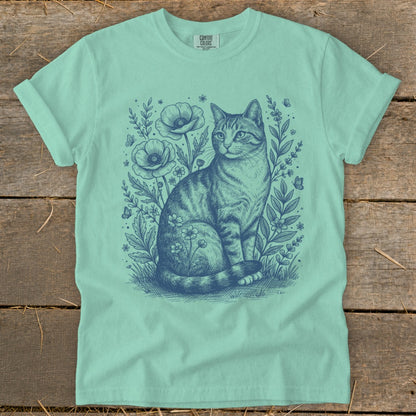 Tabby cat sitting among flowers and butterflies, graphic design on t-shirt.