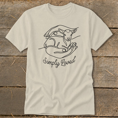 Light beige t-shirt with line art of hands holding a lamb and text "Simply Loved".