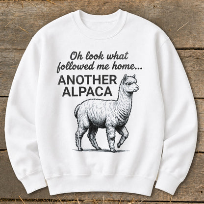 White sweatshirt with black text and alpaca illustration reading "Oh look what followed me home... ANOTHER ALPACA".