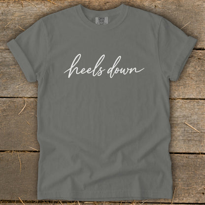 Grey t-shirt with white cursive text "heels down" and a Comfort Colors tag.