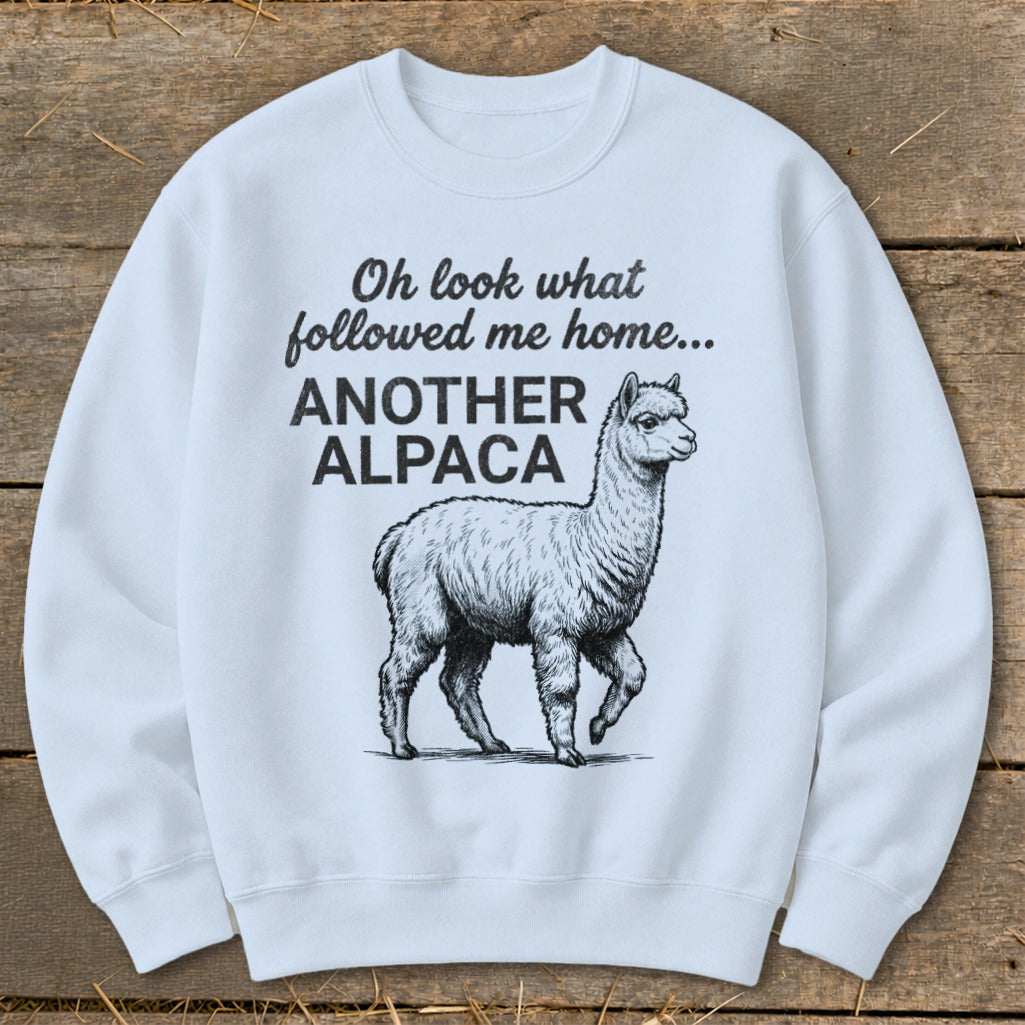 White sweatshirt with text "Oh look what followed me home... ANOTHER ALPACA" and an alpaca illustration.