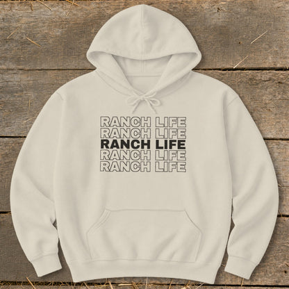 Cream-colored hooded sweatshirt featuring stacked black text reading Ranch Life centered on the chest, laid flat on a rustic wooden background.